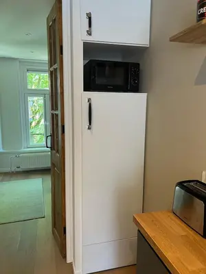 a white refrigerator with a microwave on top of it at Museum district, beautiful renovated house in Amsterdam