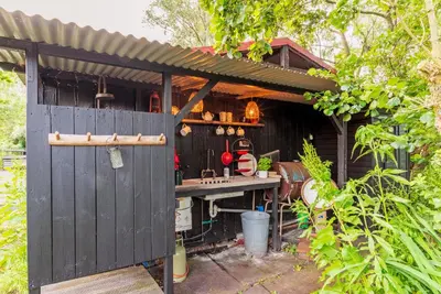 an outdoor kitchen with a shed with a gate at Nature lovers Your own island in Wijdewormer