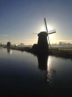 a silhouette of a windmill with the sun setting behind it at Duinrust in Egmond aan Zee