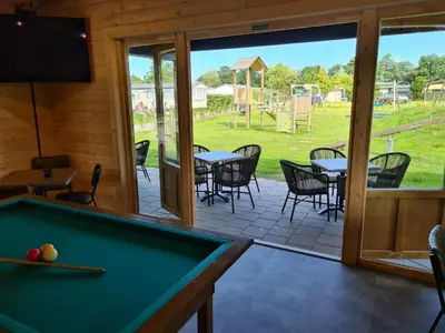 a room with a pool table and a patio at Vakantiehuis met sauna op Recreatiepark de Wielen - 64 in Sint Maarten