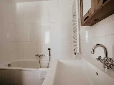 a white bathroom with a sink and a bath tub at Waterbase in Uitgeest