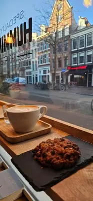 a cup of coffee and a cookie sitting on a table at Cozy Room in Oldwest with private bathroom in Amsterdam