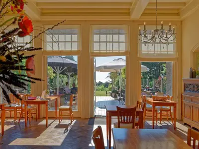 a dining room with tables and chairs and windows at Apartment in Bergen near the Beach in Bergen aan Zee