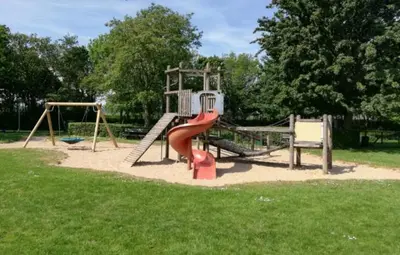 a playground with a red slide in a park at Huisje aan het einde - 273 in Warmenhuizen
