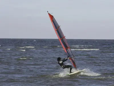 a man on a surfboard with a sail on the ocean at Holiday Home Haus Jeff by Interhome in Wervershoof