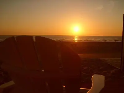 a bench on the beach watching the sunset at Holiday Home Strandhaus direkt am Meer by Interhome in Wijk aan Zee
