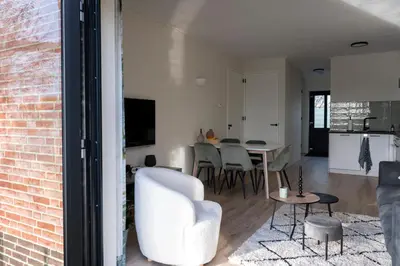 a living room with a white chair and a table at 10 persons Tulpenacker Comfort in Roelofarendsveen