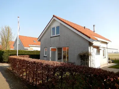 a gray house with an orange roof next to a hedge at Holiday Home Stern Comfort-1 by Interhome in Noordwijk