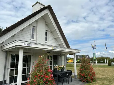 a white house with a table and flowers in front of it at Holiday Home Stern Comfort-1 by Interhome in Noordwijk