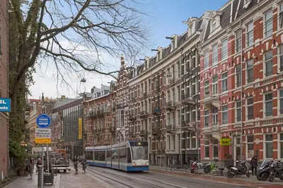 a bus driving down a city street with buildings at Marnix360apartments Design in Amsterdam