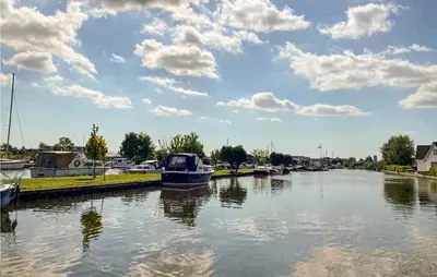 a boat is docked in a river with clouds in the sky at Awesome Home In Breukelen in Breukelen