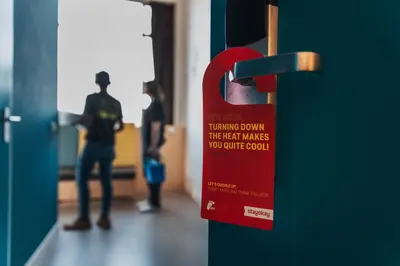 a red sign on a door with people standing in a hallway at Stayokay Hostel Utrecht Centrum in Utrecht