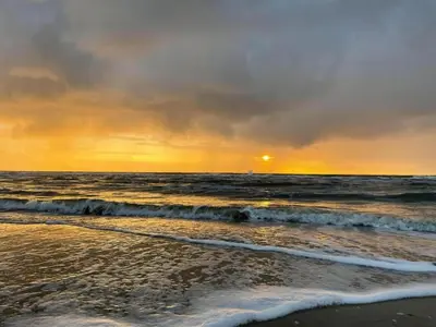 a sunset on the beach with the ocean at Holiday Home Egmond near Beach in Egmond aan Zee