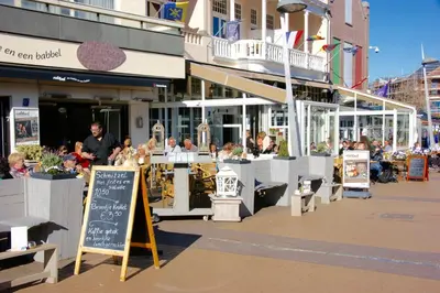 a group of people sitting at tables outside a restaurant at Reumann Holiday Apartments De Schelp 47 in Zandvoort