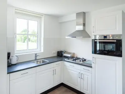 a kitchen with white cabinets and a sink and a window at Holiday Home Alk 8-1 by Interhome in Noordwijkerhout