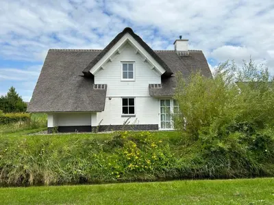 a white house with a gray roof on top of a field at Holiday Home Tapuit 6-2 by Interhome in Noordwijk