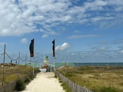 a path leading to a building on a beach with flags at Holiday Home Tapuit 8-1 by Interhome in Noordwijk