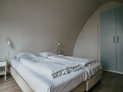 a large white bed in a room with a white wall at Apartment in Egmond with Stunning Sea Views in Egmond aan Zee