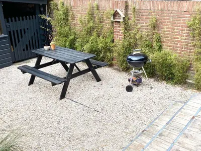 a picnic table and a grill in front of a brick wall at Zilt Noordwijk in Noordwijk aan Zee
