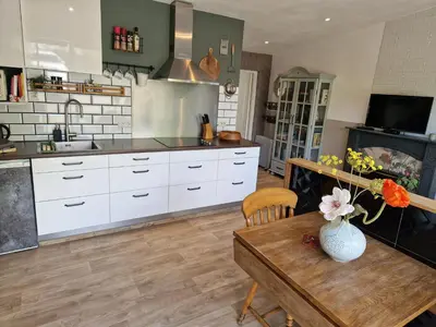 a kitchen with white cabinets and a wooden table at Bed & Bentwoud in Benthuizen