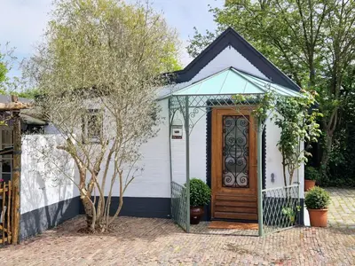 a small white house with a wooden door at Bed & Bentwoud in Benthuizen