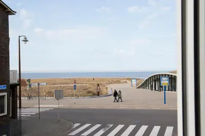 two people walking on a sidewalk near the beach at kustappartementenkatwijk in Katwijk aan Zee