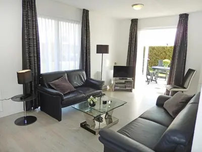 a living room with a leather couch and a table at Holiday Home Plevier Comfort-3 by Interhome in Noordwijkerhout