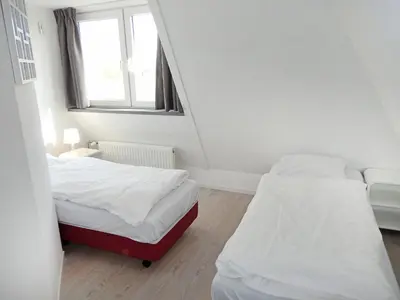 two beds in a small room with a window at Holiday Home Plevier Comfort-3 by Interhome in Noordwijkerhout