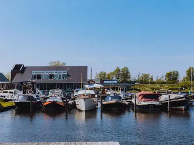 a group of boats docked in the water near a building at Holiday Home Assum by Interhome in Uitgeest