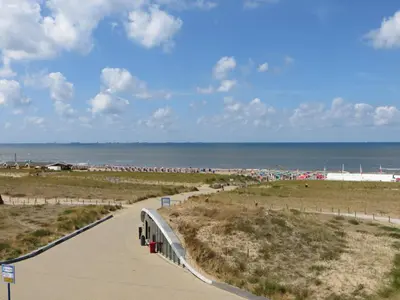 a walkway to the beach with the ocean in the background at Appartementen Zeezicht in Katwijk aan Zee