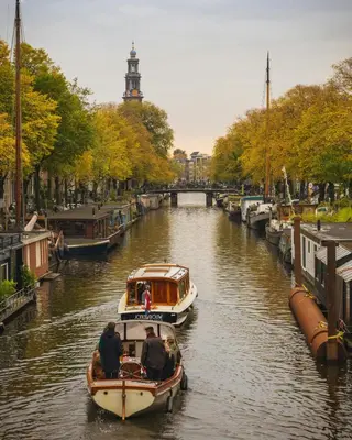 two boats in a canal with people on them at Newly renovated houseboat The Waterhouse in Amsterdam