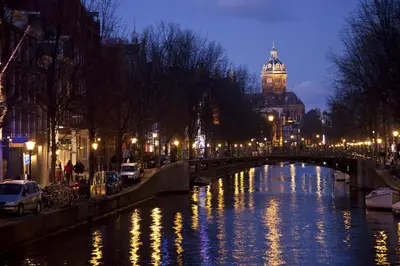 a river with a bridge and a building with a clock tower at Nachtwacht Apartment in Amsterdam
