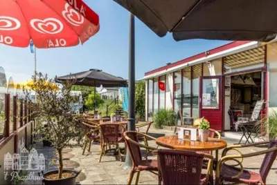a patio with tables and chairs and an umbrella at Chalet Joleen IJmuiden aan zee, vlakbij het strand in IJmuiden