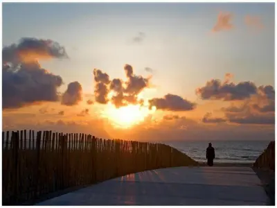 a person standing on a beach with the sunset at Holiday Home in Noordwijk near the Beach in Noordwijk