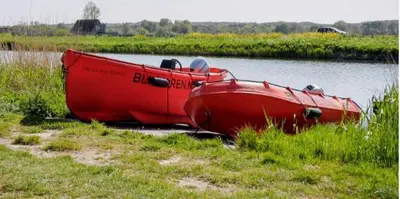 a red boat sitting on the side of a river at Rekerlanden 154 in Schoorldam