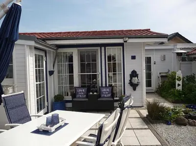 a patio with a table and chairs and a house at Ferienpark Vislust Haus De Graaf Niederlande Ijsselmeer in Wervershoof