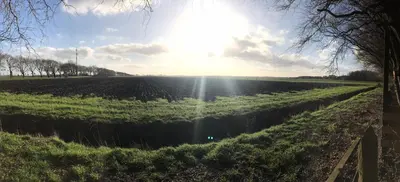 a field with the sun shining on the horizon at Landzicht in Woubrugge