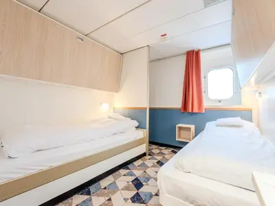 two beds in a small room with a window at DFDS Ferry - Amsterdam to Newcastle in IJmuiden