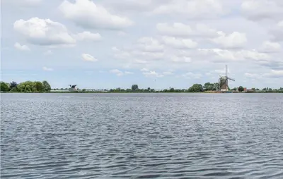 a large body of water with a windmill in the distance at Huis Nr 2 in Woubrugge