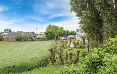 a field of grass with houses in the background at Huis Nr 5 in Woubrugge