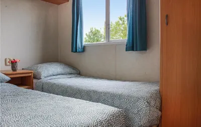 a bedroom with two beds and a window with blue curtains at Huis Nr 5 in Woubrugge
