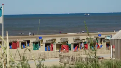 a beach with chairs and people on the beach at Beachhouse Anna, 1 minute walk to the beach and centre of Katwijk, Free private parking next to the house ! in Katwijk aan Zee