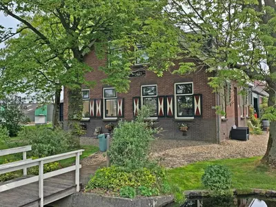 a brick house with a white fence in front of it at Christinahoeve Logies Oude Deel in Boskoop