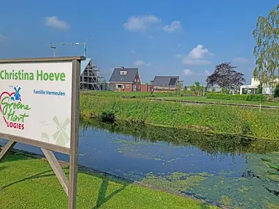 a sign in front of a river with a house at Christinahoeve Oude Deel #4 in Boskoop