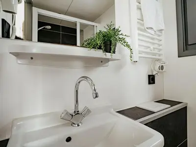 a white sink in a white bathroom with a plant at Holiday Home De Meerparel-1 by Interhome in Uitgeest