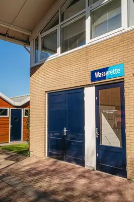 a building with two garage doors and a sign on it at Holiday Home De Meerparel-1 by Interhome in Uitgeest