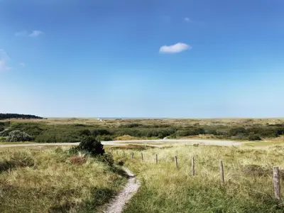 a cloud in the sky over a field with a fence at Modern holiday home near Schoorl and beach in Schoorldam