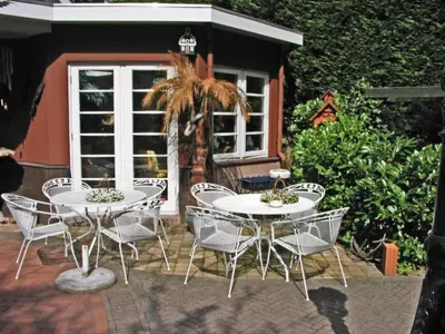 a patio with two tables and chairs and a palm tree at Villa Prinsenhof # Vierendertig in Bergen