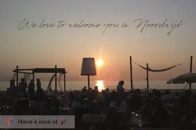 a group of people watching the sunset on the beach at Have a nice stay! - Blue Beach House 350 meters from sea in Noordwijk aan Zee