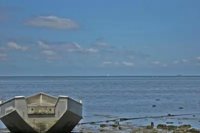 a boat sitting on the shore of the ocean at Hotelhuisje Warmenhuizen #A in Warmenhuizen